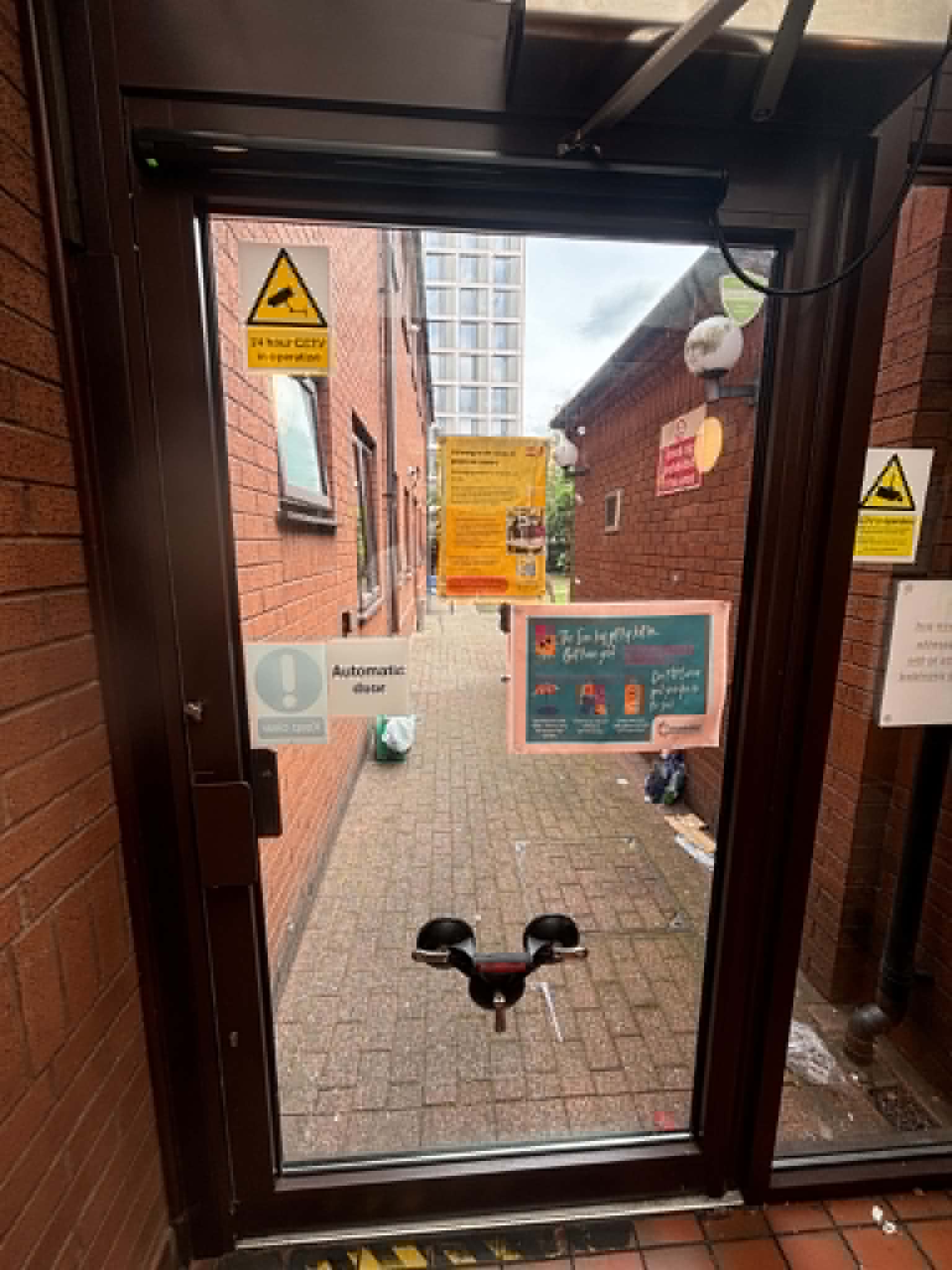 Automatic door sensor and signage on a commercial entrance in Manchester